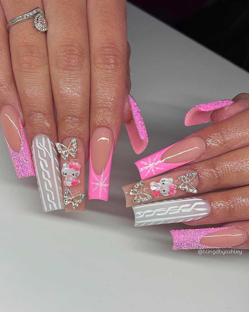 Glamorous pink coffin nails with glitter, 3D bows, and white winter knit patterns.