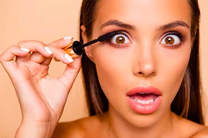 Woman Applying Mascara Mouth Open Curlers In Hair