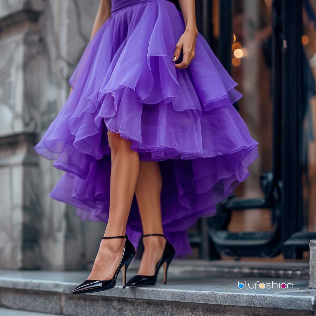 Woman in a whimsical purple ruffled dress paired with classic black stilettos stepping out in style on city steps."