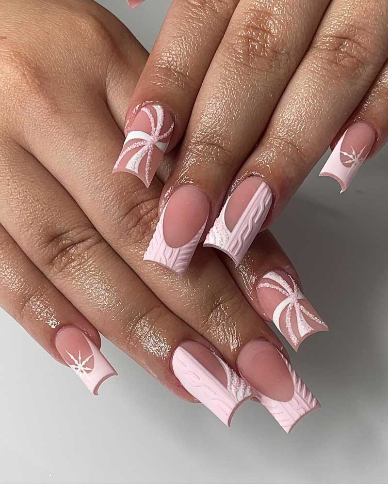 Elegant pink and white winter-themed nails with cable knit and snowflake designs.