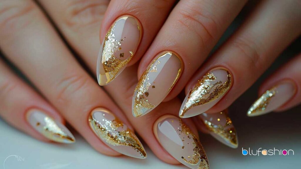 Chic stiletto nails with a beige base and gold glitter accents for a sophisticated look.