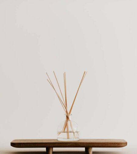 A minimalist's home decor station with a simple reed diffuser on a stand for home fragrance notes.