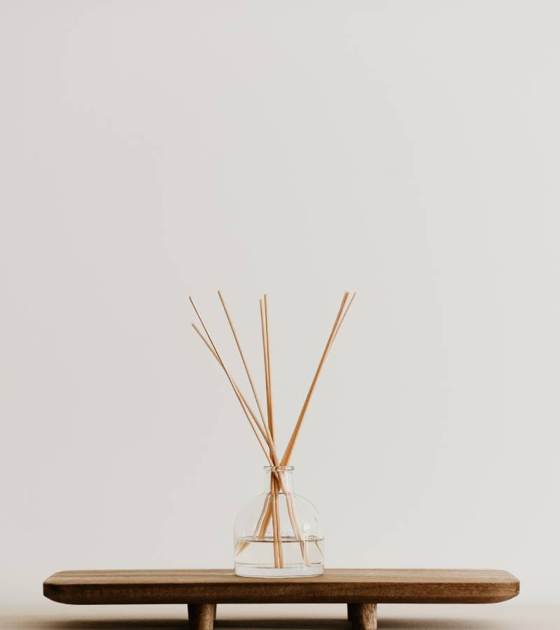 A minimalist's home decor station with a simple reed diffuser on a stand for home fragrance notes.