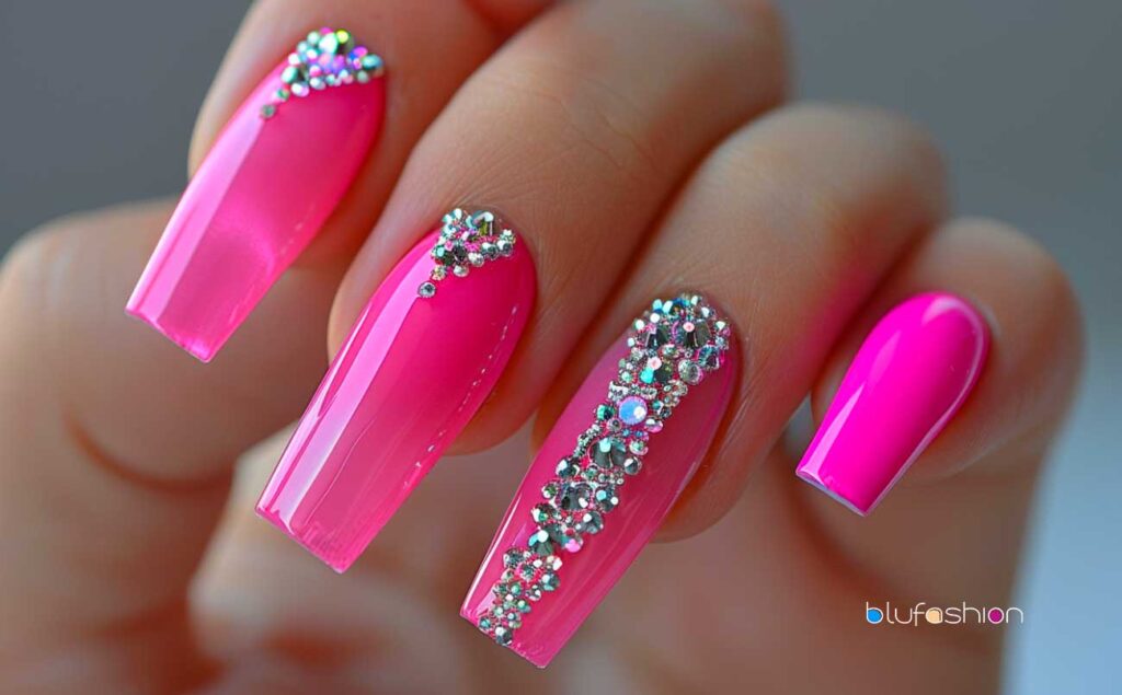 Glossy hot pink stiletto nails adorned with an intricate pattern of diamond rhinestones, showcasing a luxurious and vibrant manicure.