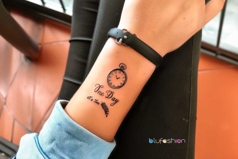 Inspirational One Day at a Time Tattoo quote with pocket watch tattoo on forearm.