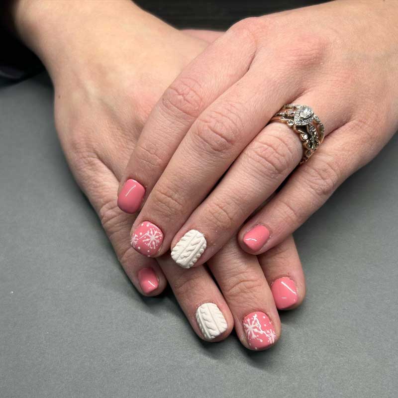 Soft pink short nails with white cable knit and snowflake designs, adorned with diamond ring.