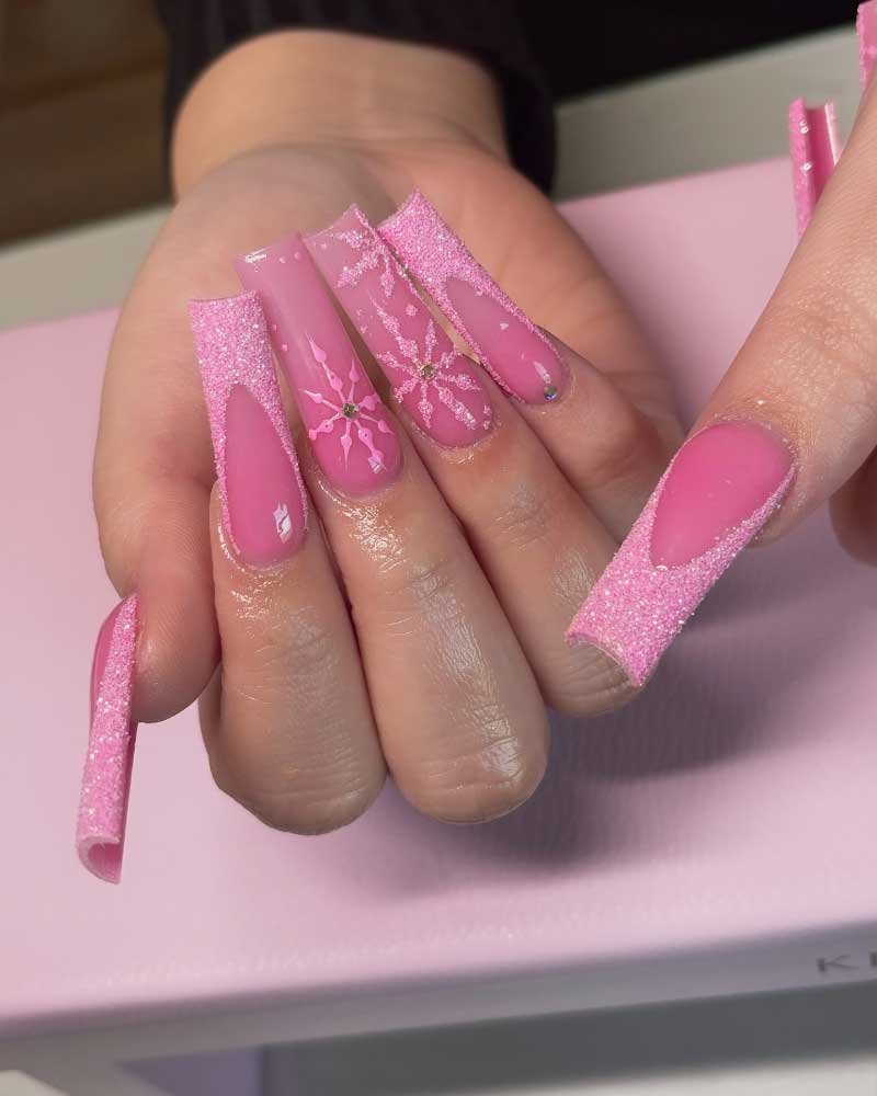 Shimmering pink long coffin nails with snowflake design and crystal embellishments.