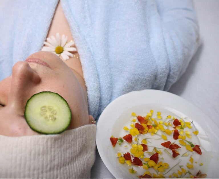 Relaxed woman with cucumber on eyes during a spa facial with flower petals in milk.